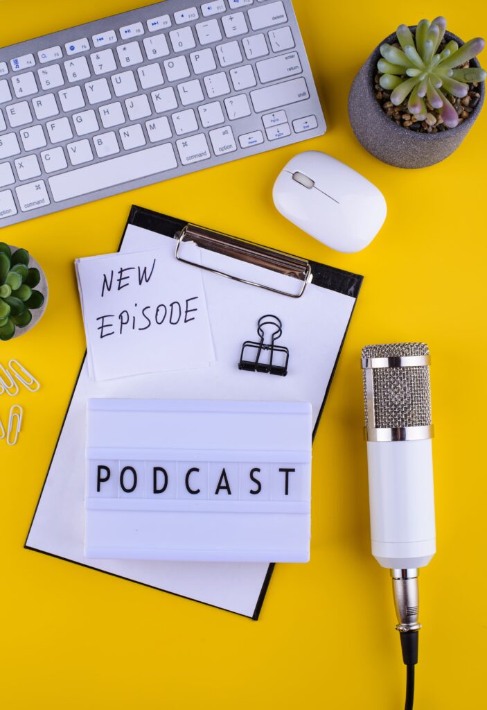 Un micro, un clavier et un bloc-notes sur lequel on peut lire le mot "podcast"