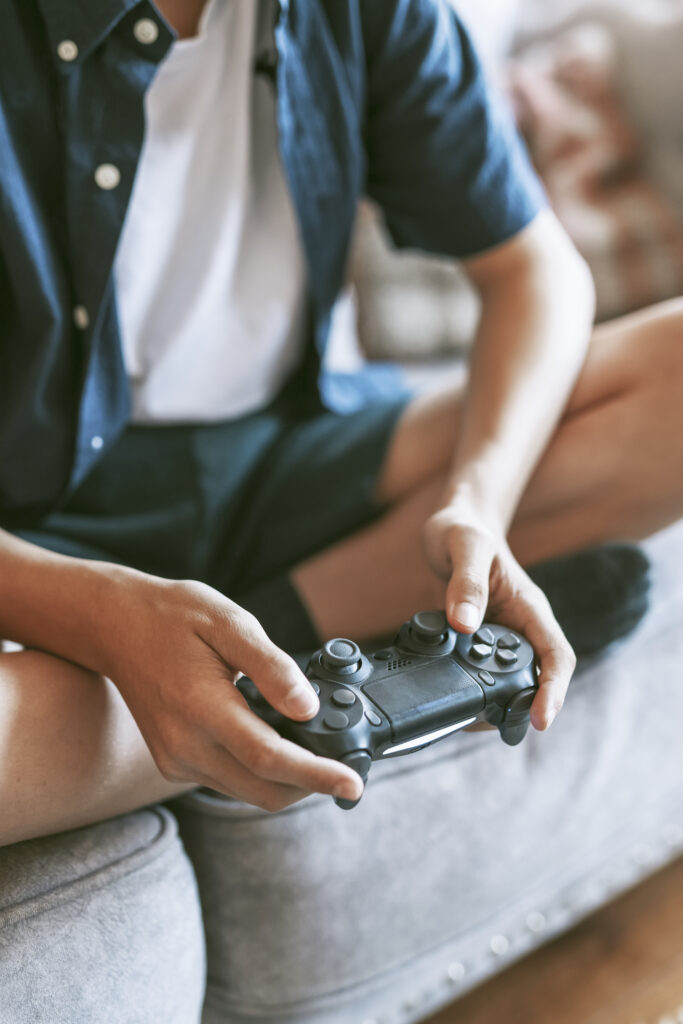 Un jeune homme tient une manette de console de jeux vidéo