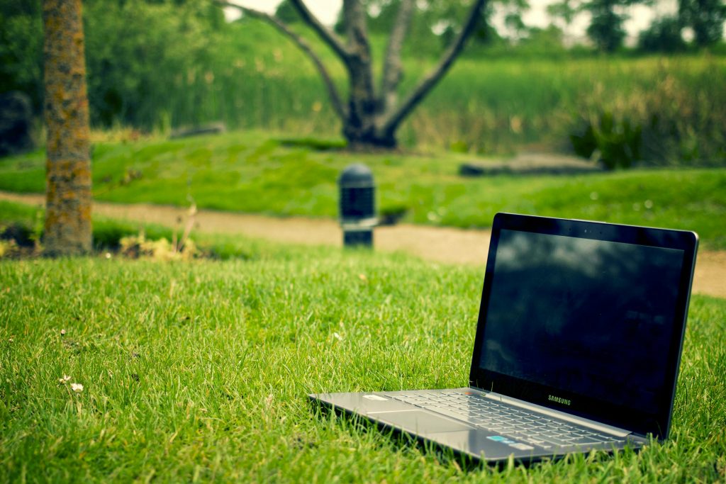 Un ordinateur portable posé sur l'herbe dans un parc. Cette photographie illustre le concept de numérique responsable.